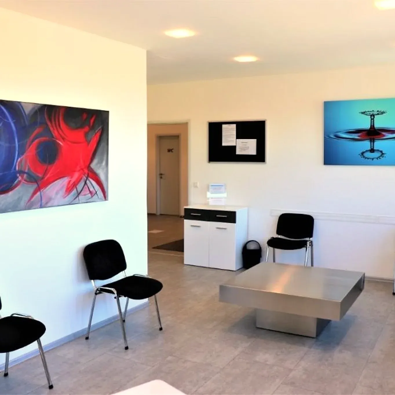 Wartebereich der Praxis mit Sitzgruppe und Bildern an der Wand